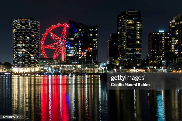 docklands city skyline and melbourne star observation wheel illuminated at night - melbourne city at night stockfoto's en -beelden