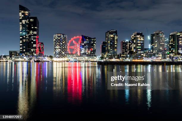 docklands city skyline and melbourne star observation wheel illuminated at night - melbourne night stock pictures, royalty-free photos & images