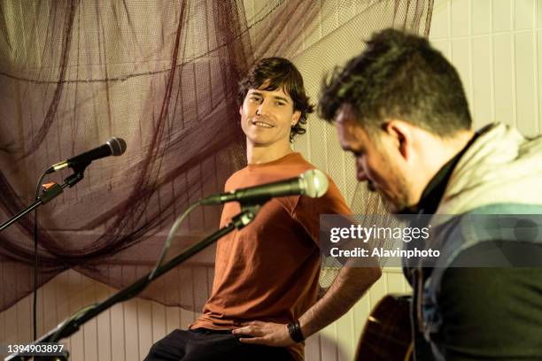 couple of musicians singing and playing at a concert in a pub with colored lights illumination - music pub foto e immagini stock