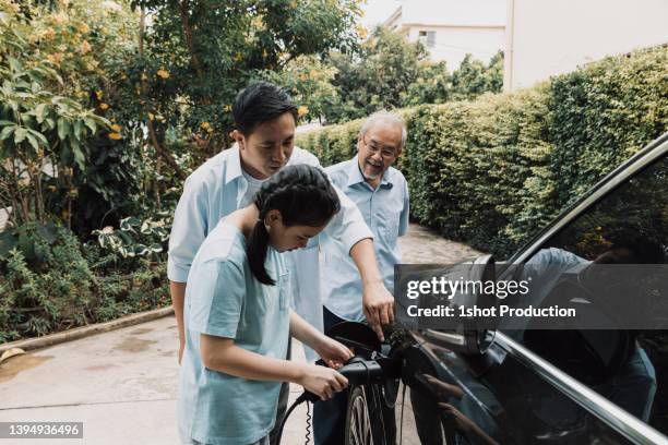 father explaining use of electric car charger. - electric car home stock pictures, royalty-free photos & images