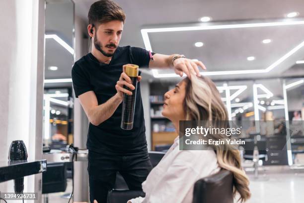 coiffeur utilisant de la laque au salon de beauté - hairdresser stock photos et images de collection