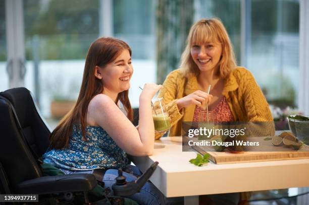 friends laughing together and drinking vegan smoothie in kitchen. - motorized wheelchair stock pictures, royalty-free photos & images