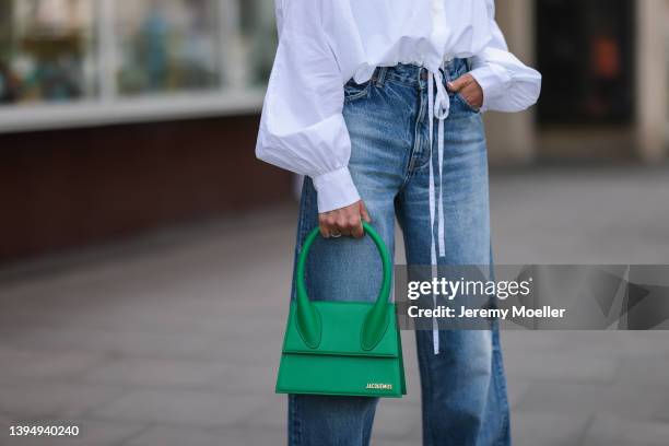 Sue Giers seen wearing a dark blue wide leg denim jeans from Celine, a white SoSue blouse shirt and a green Jacquemus Chiquito leather bag on April...