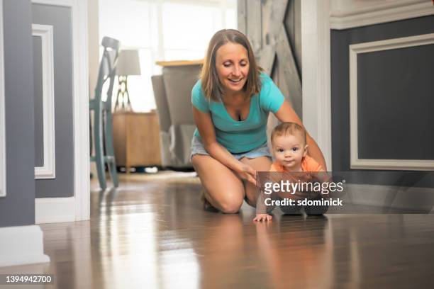 mother assisting crawling 8 month old son - hardwood 個照片及圖片檔