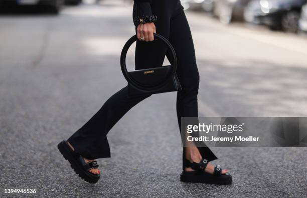 Sue Giers seen wearing a black split leggings from SoSue, black logo sandals from Celine, a black logo Celine bracelet and a black leather Jacquemus...
