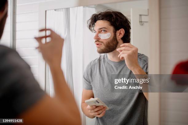 handsome young man wearing an collagen under eye patch - man eye cream stock pictures, royalty-free photos & images