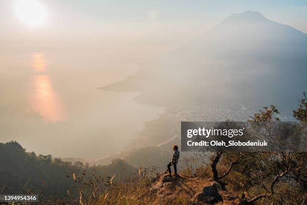 man standing on mountain on  the background of atitlan lake in guatemala at sunset - lake atitlan stock pictures, royalty-free photos & images