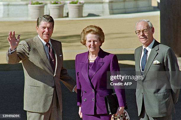 Former US President Ronald Reagan salutes next to former British Prime Minister Margaret Thatcher and her husband Denis Thatcher as she arrives to...