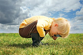 Little Boy Exploring Nature Outside with Magnifying Glass