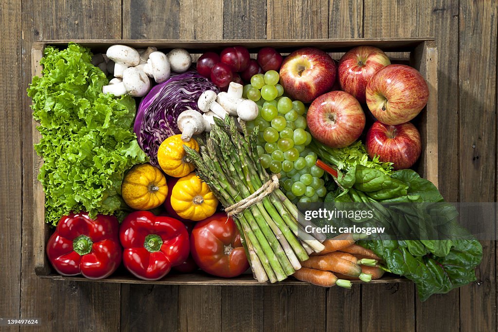 Crate full of fruits and vegetables over rustic table