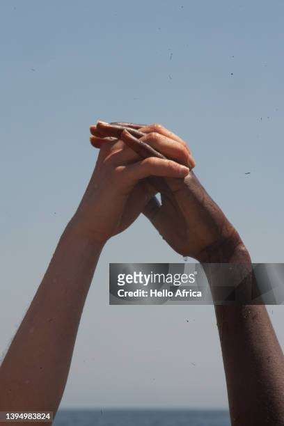 close-up of mixed race and sex hands held up with the ocean on the horizon & clear blue sky for background - blue sky friends photos et images de collection