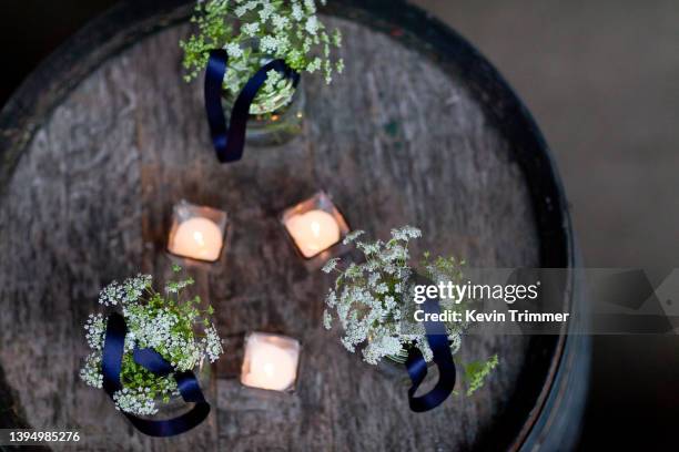 rustic cocktail hour centerpiece with candles and flowers atop old wine barrel - floral cocktail hour bildbanksfoton och bilder