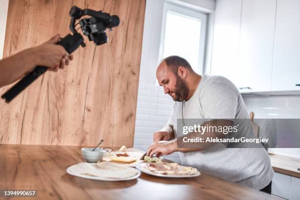 cuoco maschio barbuto che viene registrato mentre prepara i tacos a casa - fat guy foto e immagini stock