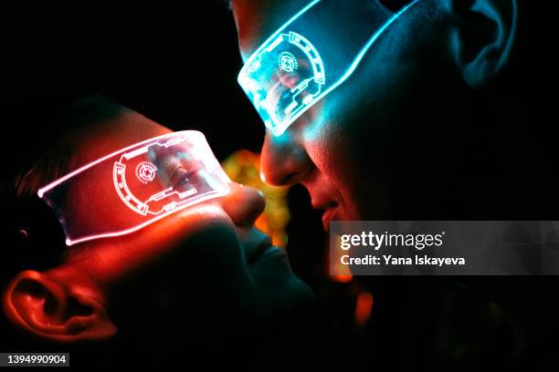 portrait of a futuristic couple in love looking at each other in illuminated vr glasses - love at first sight stock-fotos und bilder