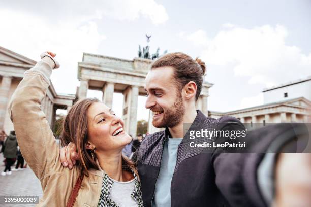 couple take a snaps from their latest trip - brandenburg gate berlin stockfoto's en -beelden
