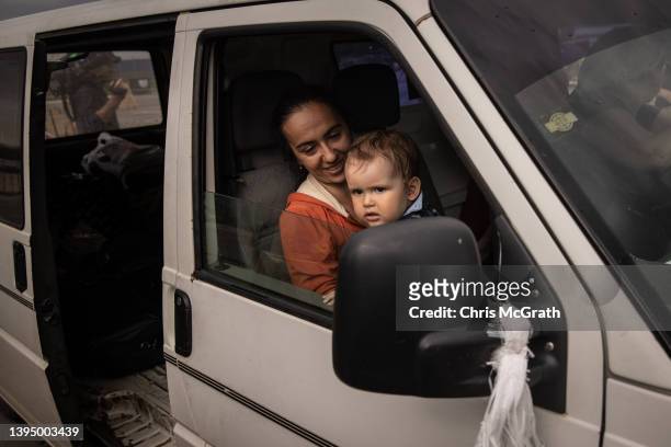 Woman sits with her baby in their car after arriving at an evacuation point for people fleeing Mariupol, Melitopol and the surrounding towns under...
