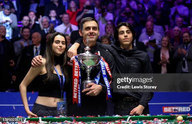 Ronnie O'Sullivan of England poses with the Betfred World Snooker Championship trophy along with members of his family after winning the Betfred...