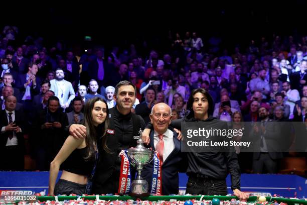 Ronnie O'Sullivan of England poses with the Betfred World Snooker Championship trophy along with members of his family and Fred Done, Owner of...
