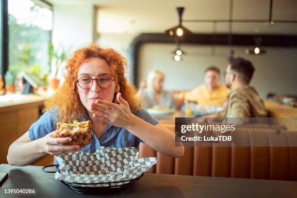 a portrait of a woman who enjoys eating her favorite hamburger. - burger king imagens e fotografias de stock