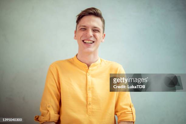 a portrait of a man with a happy facial expression standing in front of a white background. - yellow blouse stockfoto's en -beelden