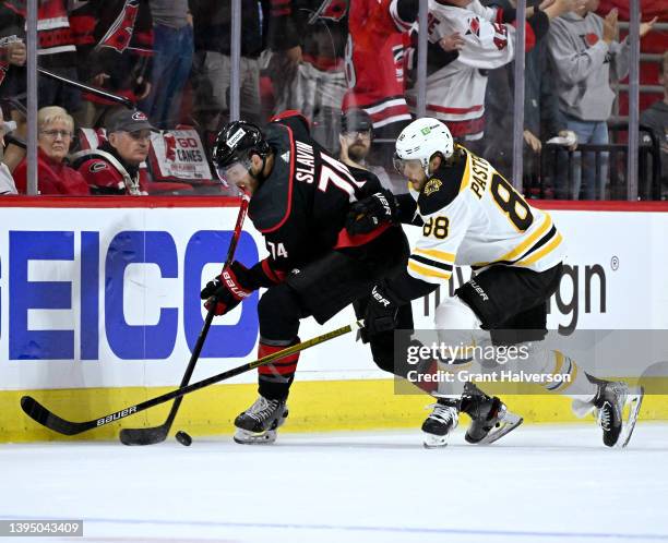 Jaccob Slavin of the Carolina Hurricanes and David Pastrnak of the Boston Bruins battle for the puck during the first period of Game One of the First...