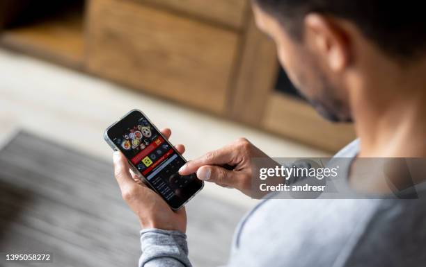 homme jouant en ligne sur un match de football en utilisant son téléphone portable - joue photos et images de collection