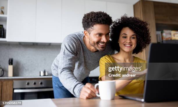 couple at home making a reservation online using their laptop - couple stockfoto's en -beelden