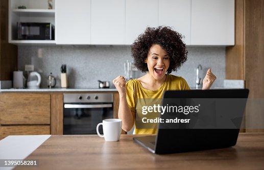 Excited woman at home working on her laptop and winning something Excited woman at home working on her laptop and winning something