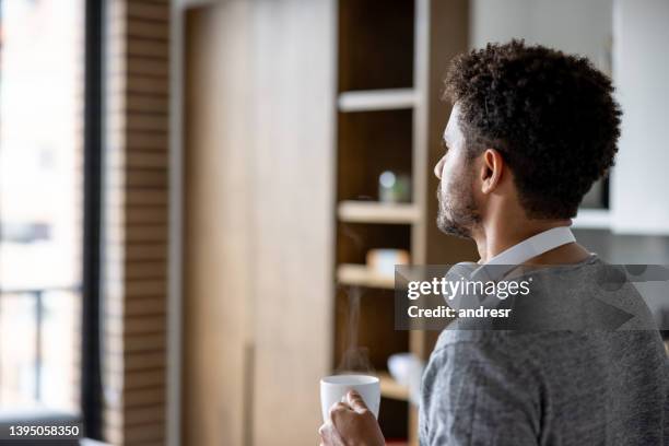 nostalgic man drinking a cup of coffee at home - headphone man on neck stockfoto's en -beelden