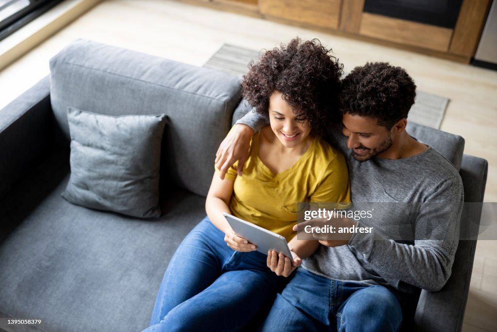 Happy couple choosing a movie to watch online on their tablet