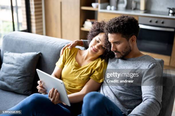 loving couple at home watching a movie online on a tablet - home movie stock pictures, royalty-free photos & images