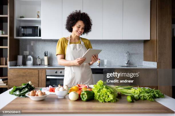 happy woman cooking at home following an online recipe - following recipe stock pictures, royalty-free photos & images