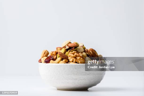 mix nuts and dry fruits in a bowl with white background - bowl stock-fotos und bilder