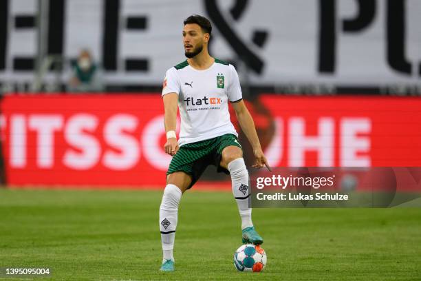 Ramy Bensebaini of Mönchengladbach runs with the ball and gestures during the Bundesliga match between Borussia Mönchengladbach and RB Leipzig at...