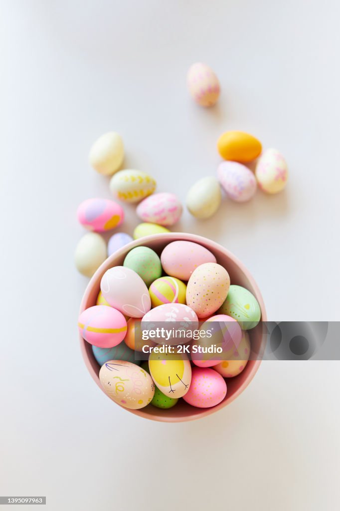 A pink bowl of brightly colored decorated Easter eggs