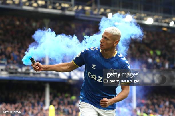 Richarlison of Everton celebrates with a flare after scoring their team's first goal during the Premier League match between Everton and Chelsea at...