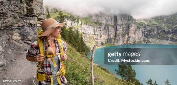 young woman hiking in a beautiful alpine scenery in summer walking in the swiss alps enjoying nature and the outdoors - discovery bags walking stockfoto's en -beelden