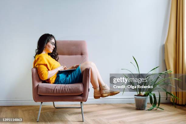 young female worker using phone and chilling at free time, connecting with colleagues by laptop in relaxation room with plant. copy space - laptop studio shot stock pictures, royalty-free photos & images