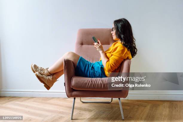 young female worker in casual outfit using phone and resting at free time, connecting with colleagues - wooden floor white background stock pictures, royalty-free photos & images