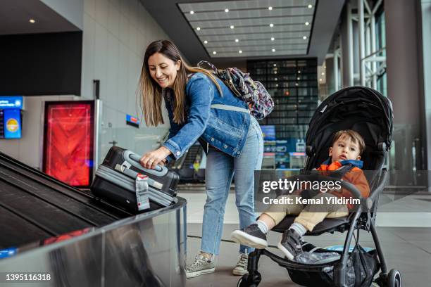 single mother and her son waiting for luggage near conveyor belt - baby gate imagens e fotografias de stock