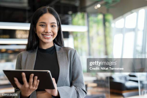 empowering women business entrepreneurs through information and communications technology solution. portrait of a young businesswomen using a tablet in a financial business office. - green suit foto e immagini stock