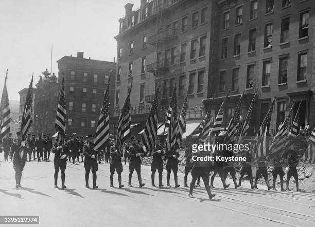 The 'Color Guard' carrying stars-and-stripes flags as the march during the annual police parade in New York City, New York, 1937. A color guard is...