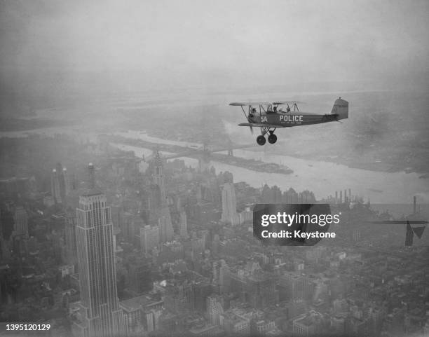 Fleet Model 1 biplane of the NYPD Aviation Unit patrolling the skies over Manhattan, with the Empire State Building in the foreground, in New York...