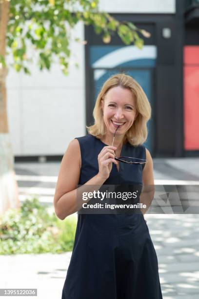 portrait of smiling elder business woman on street - eine seniorin allein stock-fotos und bilder