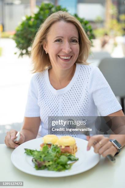 laughing woman having lunch in a cafe outdoors - eggs benedict stock pictures, royalty-free photos & images