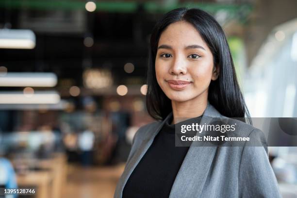 portrait of confident young businesswomen standing in a convention center during product and service launch event. global business, technology and innovation. - one young woman only photos fotografías e imágenes de stock