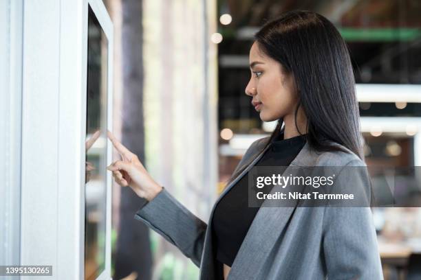 innovative framework for self-service kiosks solution. businesswomen using touch screen display to confirm order or payment of product, service at a kiosk machine. - airport shopping stockfoto's en -beelden