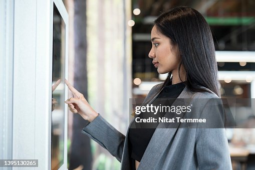 Innovative Framework for Self-service Kiosks Solution. Businesswomen using touch screen display to confirm order or payment of product, service at a kiosk machine. Innovative Framework for Self-service Kiosks Solution. Businesswomen using touch screen display to confirm order or payment of product, service at a kiosk machine.