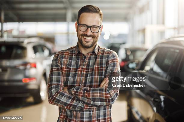 feliz cliente masculino con los brazos cruzados en una sala de exposición de automóviles. - salesman fotografías e imágenes de stock