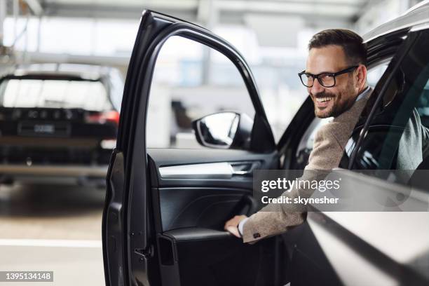 young happy man inside of a car at showroom. - car rental stockfoto's en -beelden